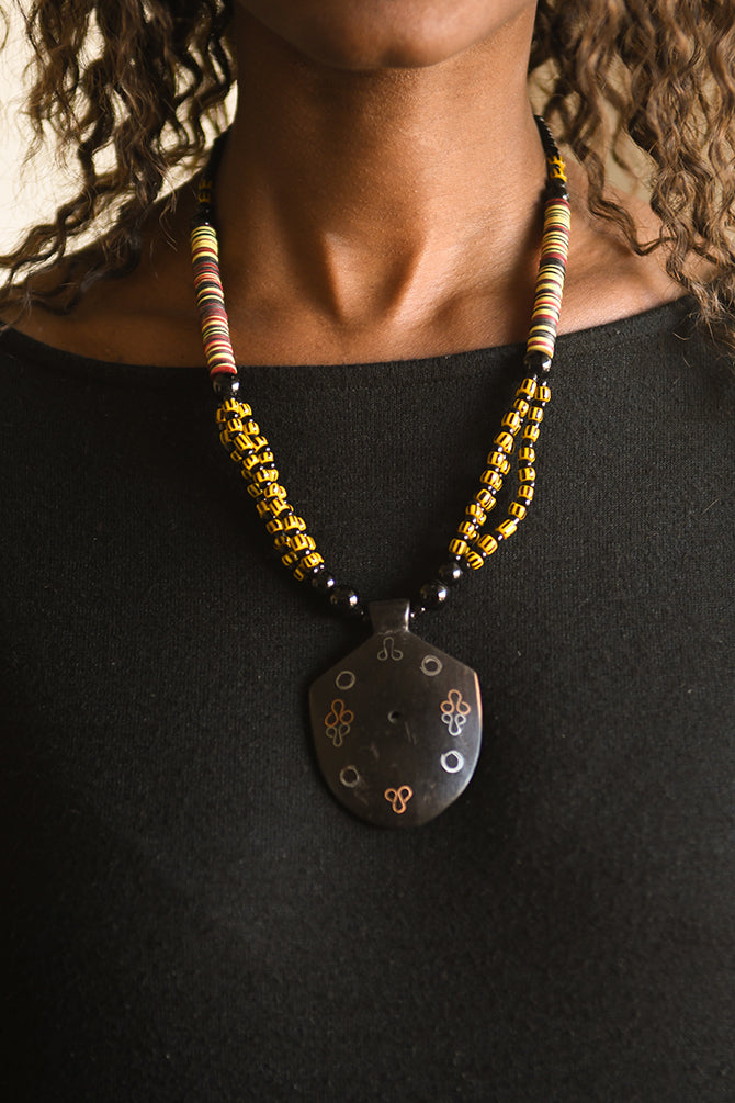Handcrafted Necklaces - Handmade - African Art - Jewelry - Beaded Necklaces - This Tribal Beaded Jewelry Necklace is handmade from African vintage chevron trade beads, assembling a unique and exotic tribal style. Each bold pendant complements the look and feel of its wooden base, creating a timeless piece for any occasion. Length: 13" Inventory # 10852