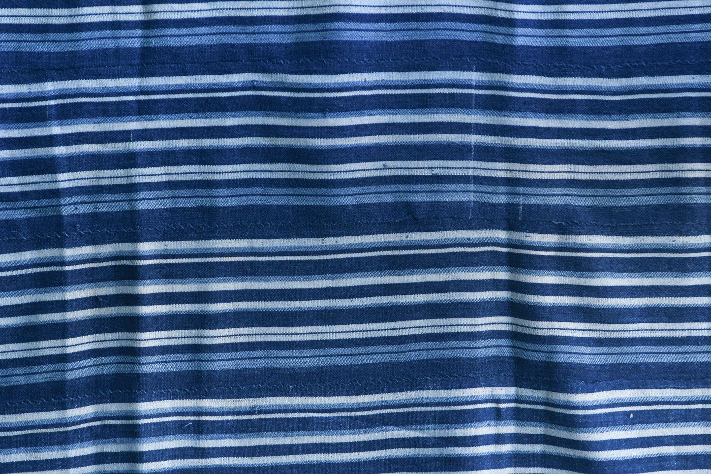 Handcrafted Textiles - Artisan Designed - Handcrafted African Art Textiles - Home Decor - Living Spaces - Mix Colors - Bold Patterns - Traditional Designs - African Culture - Add a unique piece to your home decor with this Indigo Dyed Stripe Woven Textile. This vintage faded blue cotton fabric is an authentic African Mossi textile, perfect for making a statement in any living space. Crafted with premium detail and care, it is suitable for both everyday use and collections. Length: 61 inches Width: 42 inches