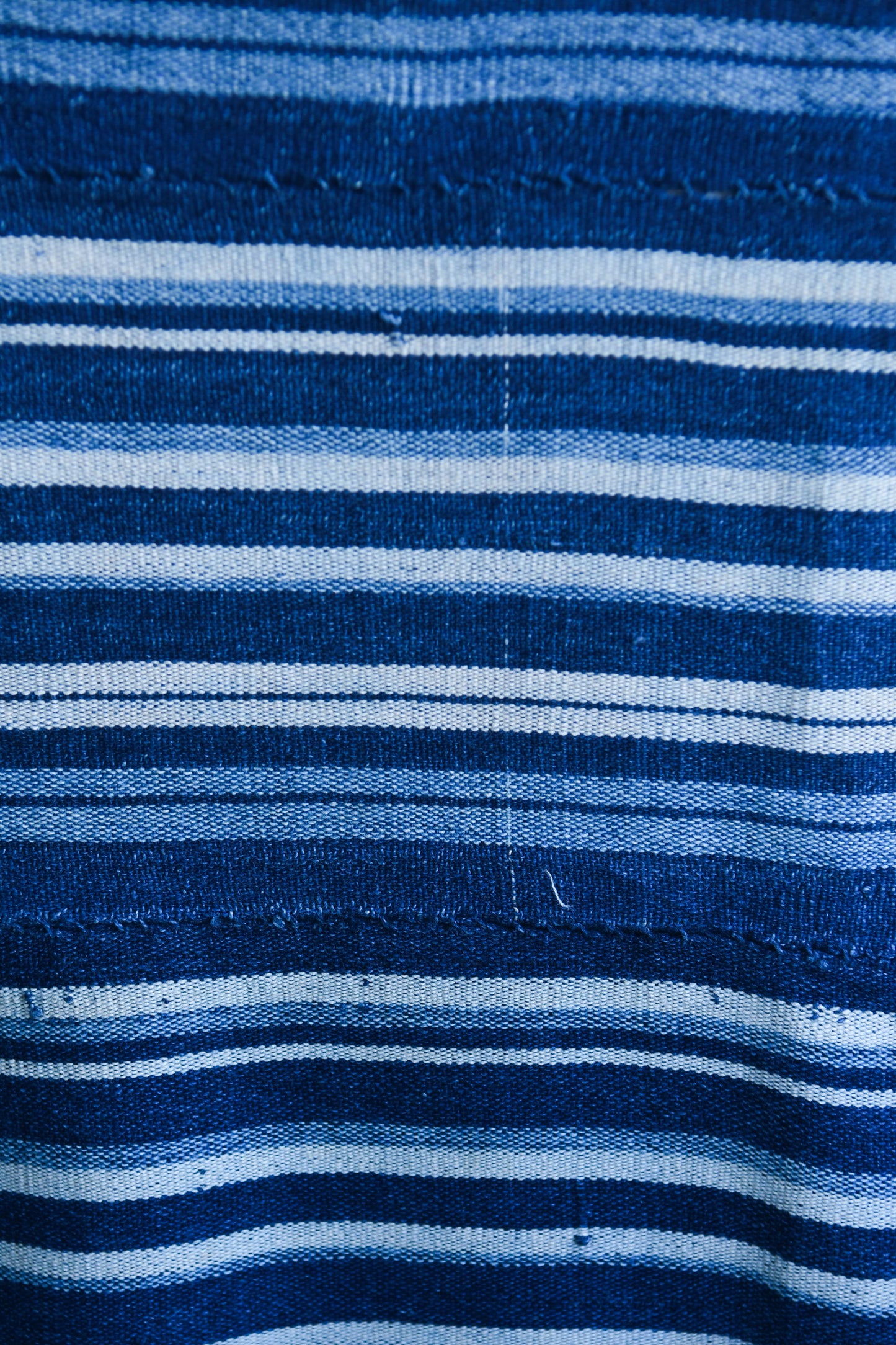 Handcrafted Textiles - Artisan Designed - Handcrafted African Art Textiles - Home Decor - Living Spaces - Mix Colors - Bold Patterns - Traditional Designs - African Culture - Add a unique piece to your home decor with this Indigo Dyed Stripe Woven Textile. This vintage faded blue cotton fabric is an authentic African Mossi textile, perfect for making a statement in any living space. Crafted with premium detail and care, it is suitable for both everyday use and collections. Length: 61 inches Width: 42 inches