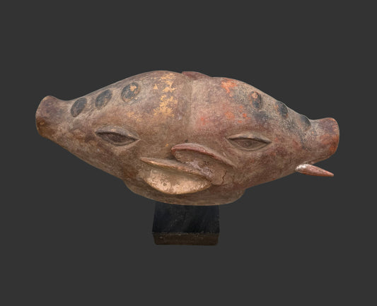 Rust-colored pig head sculpture on a gray surface