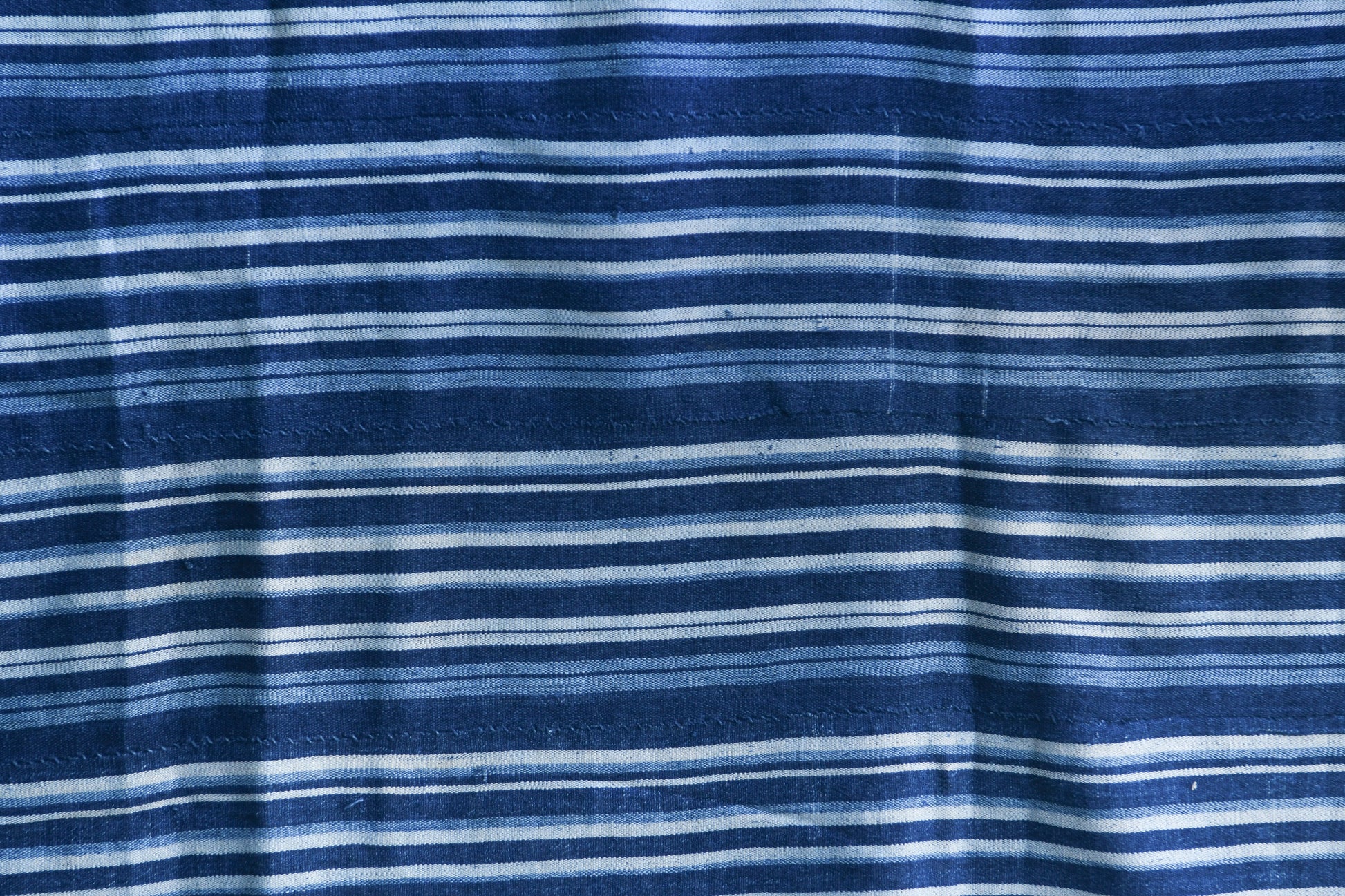 Handcrafted Textiles - Artisan Designed - Handcrafted African Art Textiles - Home Decor - Living Spaces - Mix Colors - Bold Patterns - Traditional Designs - African Culture - Add a unique piece to your home decor with this Indigo Dyed Stripe Woven Textile. This vintage faded blue cotton fabric is an authentic African Mossi textile, perfect for making a statement in any living space. Crafted with premium detail and care, it is suitable for both everyday use and collections. Length: 61 inches Width: 42 inches
